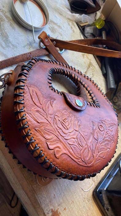 A brown leather purse is sitting on top of a wooden table.