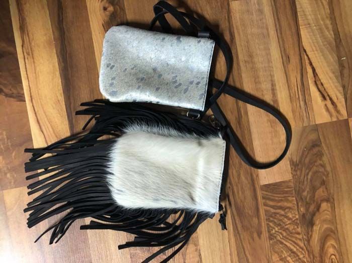 A black and white purse with fringe is on a wooden floor