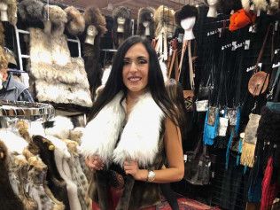 A woman is wearing a fur vest in a store.