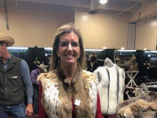 A woman is wearing a fur vest and smiling in a room.