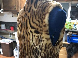 A leopard print vest is on a mannequin in a kitchen.