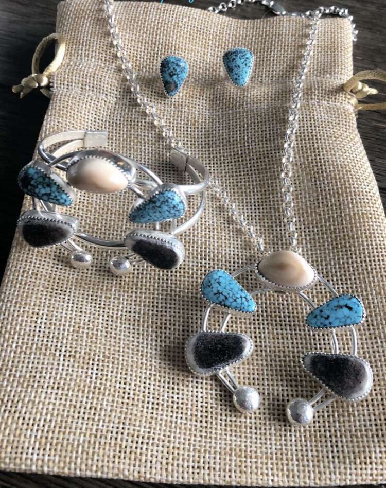 A necklace , bracelet , and earring set is sitting on a bag on a table.