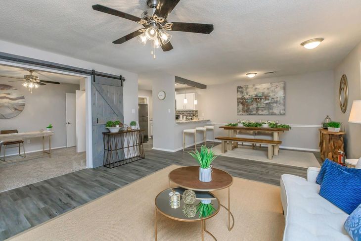Living room with wood floors, two coffee tables, dining table, and sliding door.