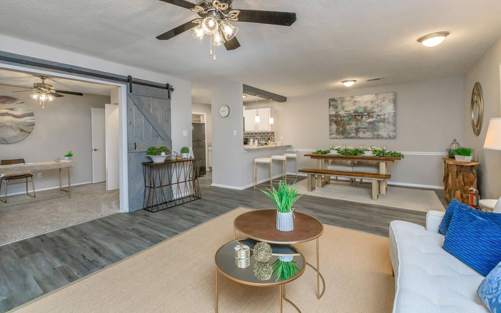 Living room with wood floors, two coffee tables, dining table, and sliding door.