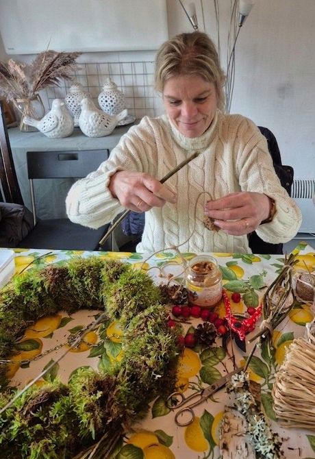 Deelnemer maakt een natuurlijke seizoensdecoratie met mos, takken en groen.