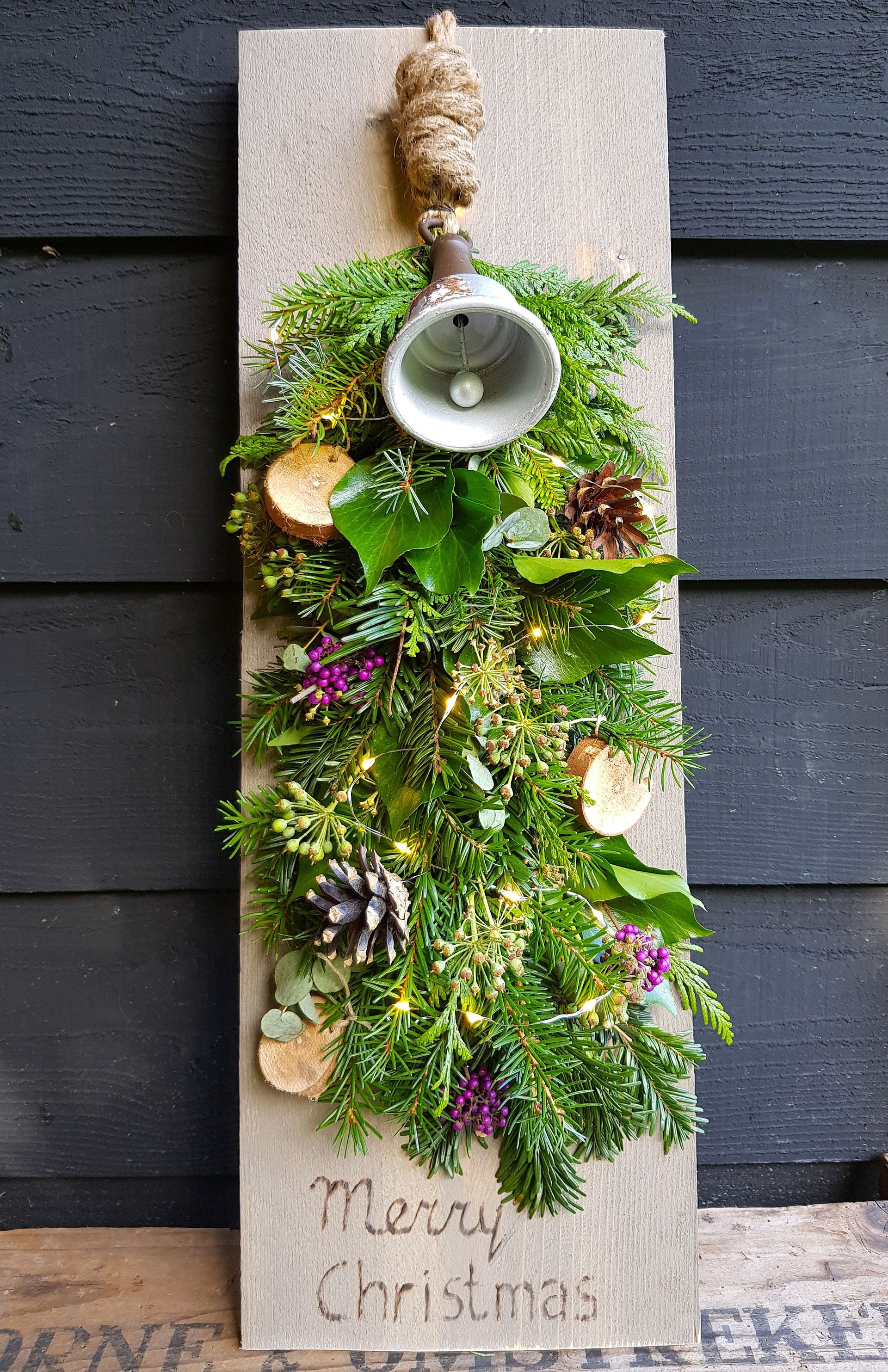 Kerstfestoen op steigerhout met houtgebrande tekst, gemaakt tijdens een creatieve seizoensworkshop.