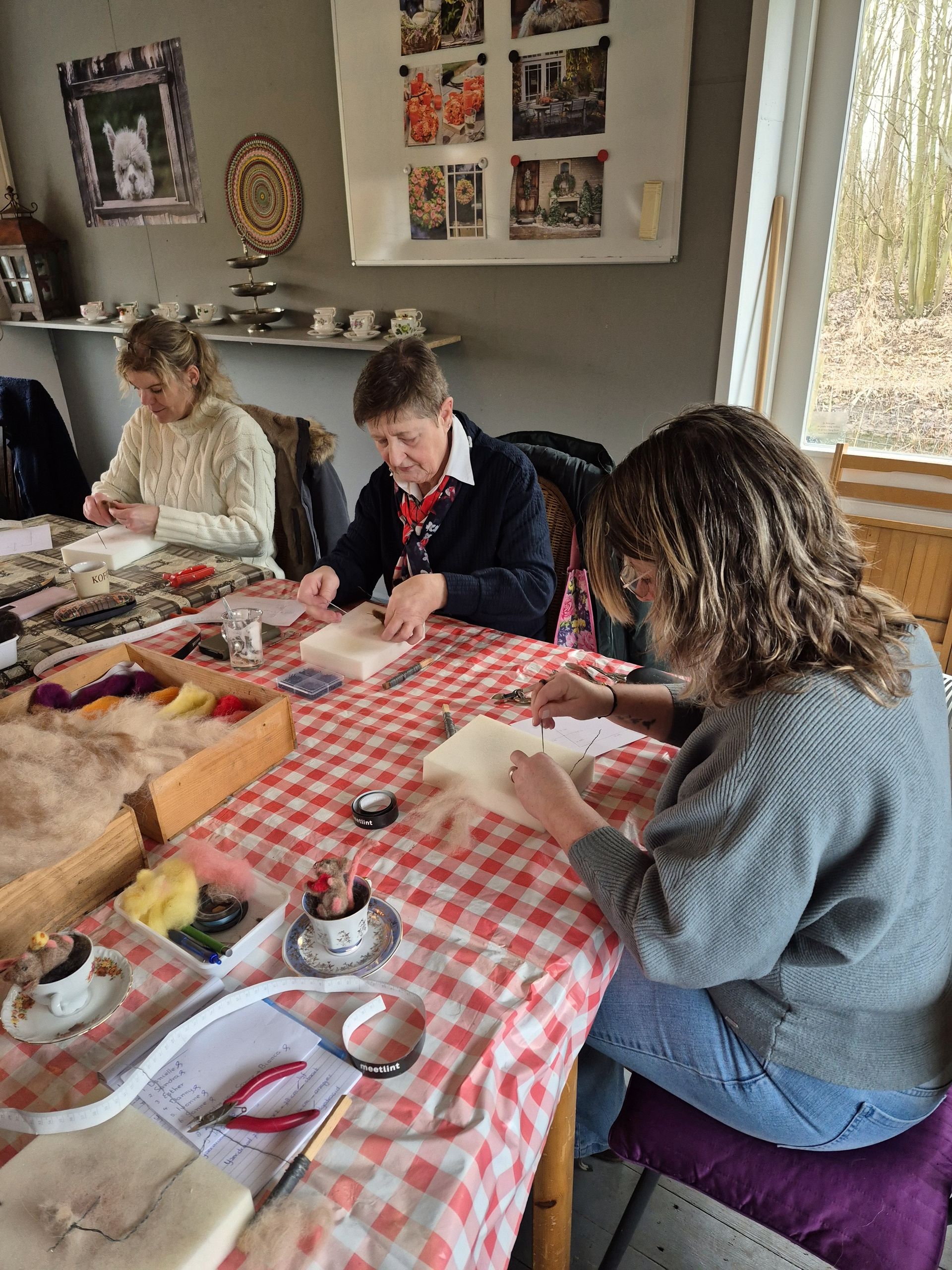 Deelnemers werken met wol aan een naaldviltwerkstuk tijdens een workshop Vilten met wol.