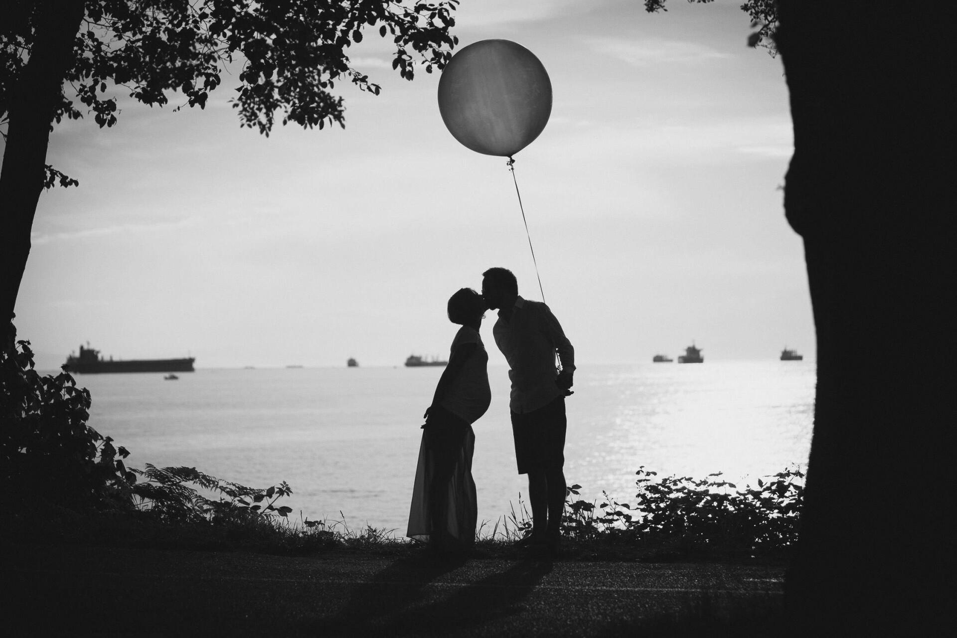 Maternity photo of a couple kissing by the water