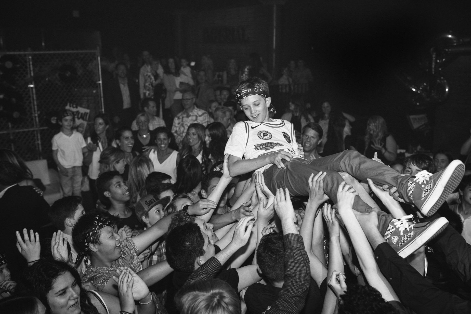A young boy being thrown up in the air at a social event