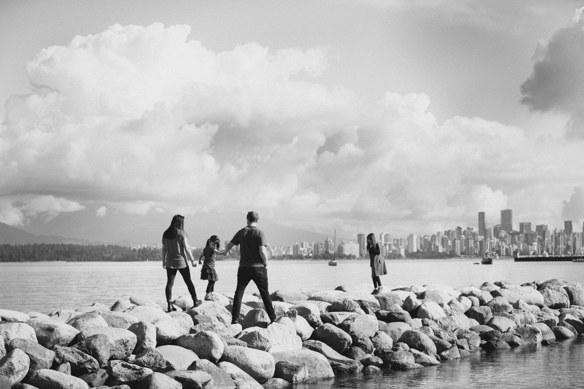 B&W photo of a family skipping down the rocks on the beach