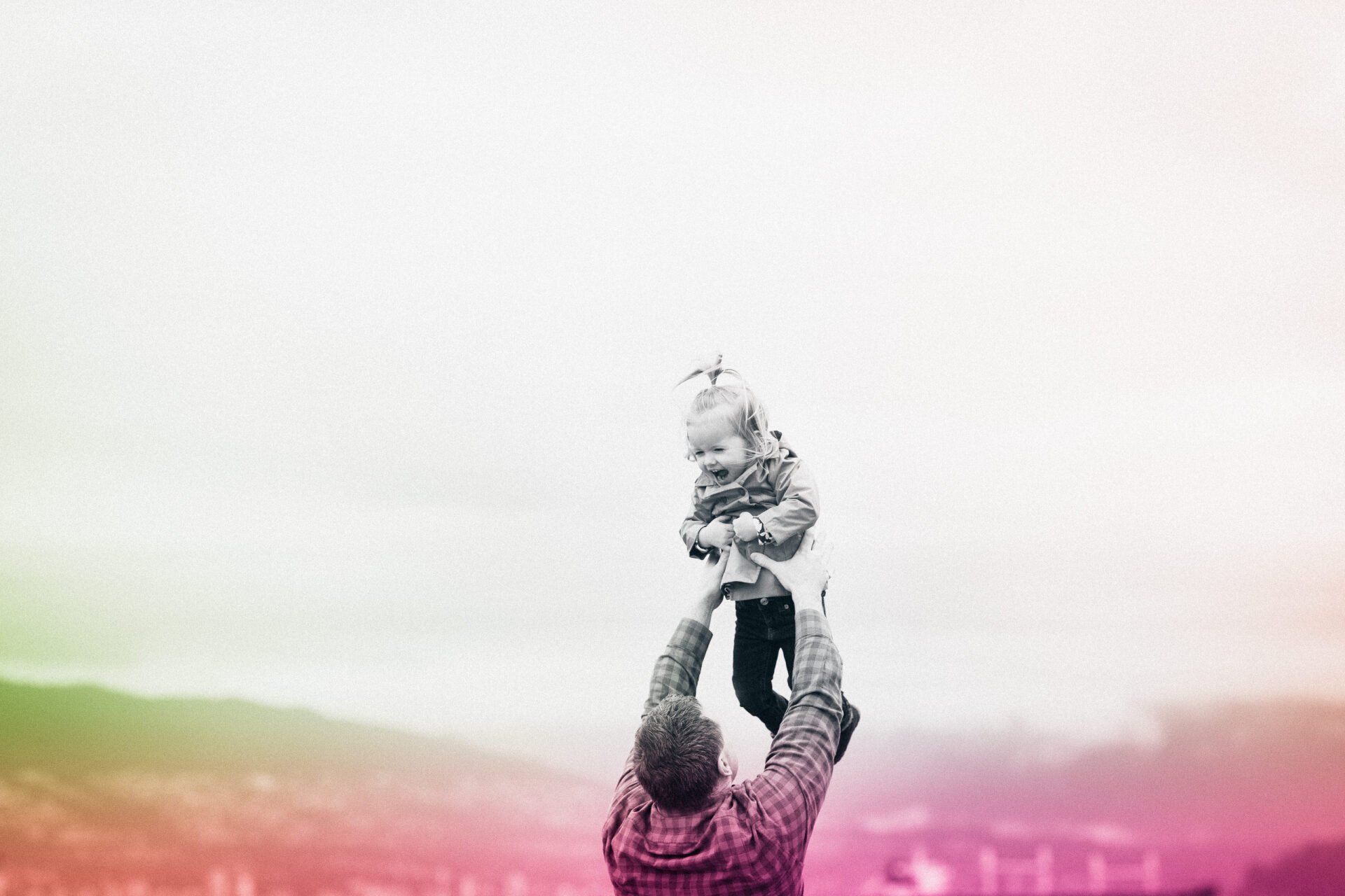 Photo of a father holding his daughter up in the air