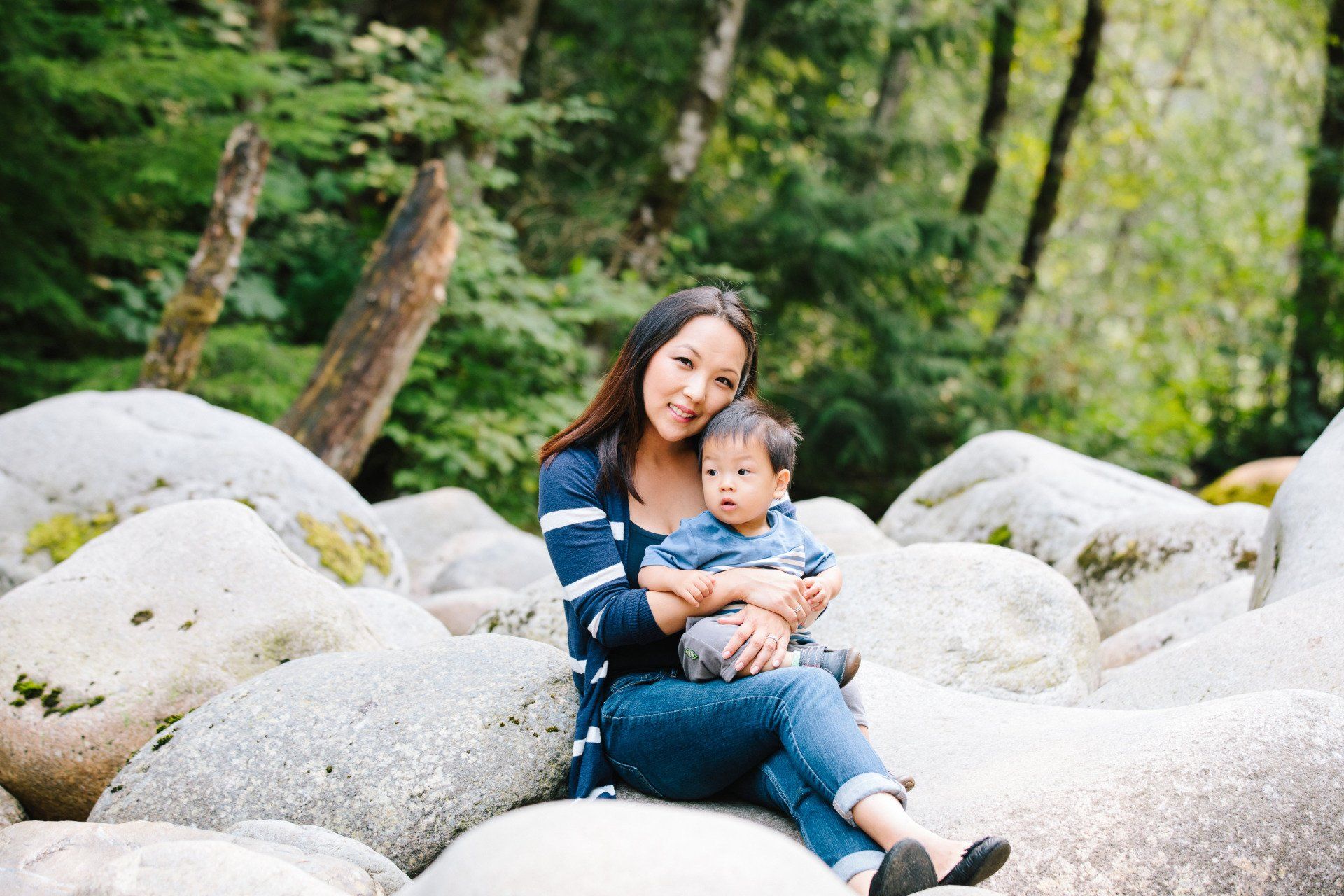 Photo of a mother sitting and holding her daughter by the forest