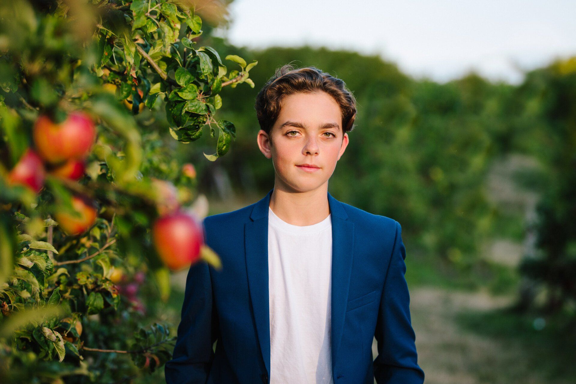 Portrait photo of a young boy by an apple tree