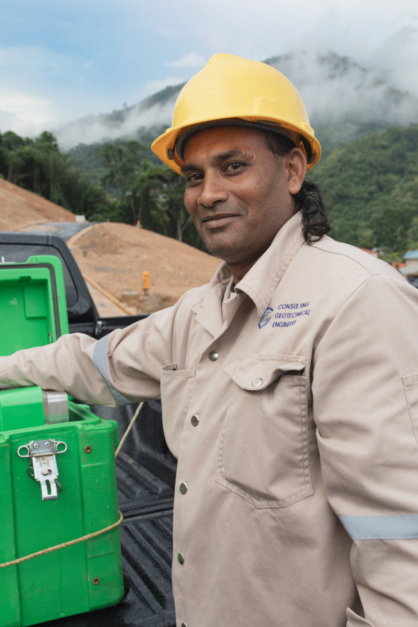 A man wearing a hard hat is standing next to a green box.