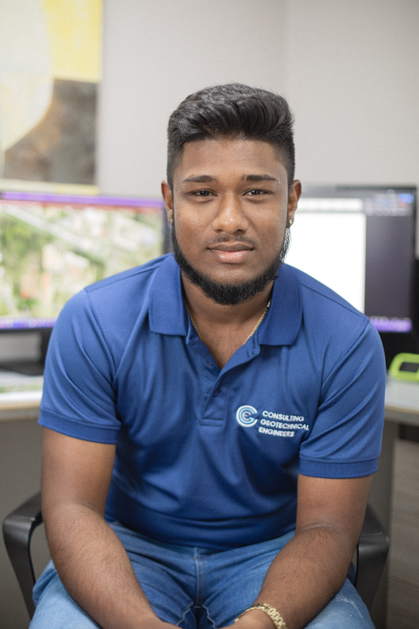 A man in a blue shirt is sitting in a chair in front of a computer.