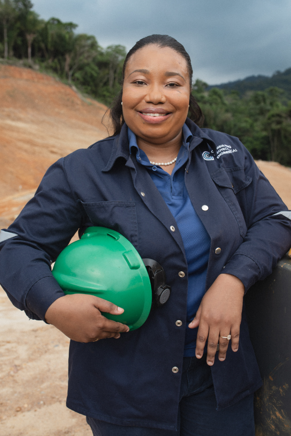 A woman in a blue jacket is holding a green hard hat.