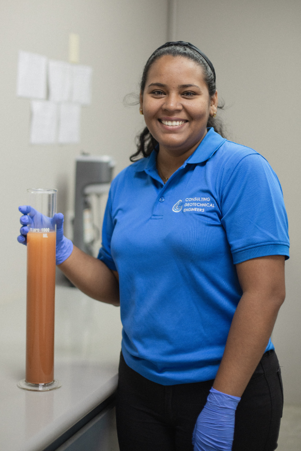 A woman in a blue shirt is holding a beaker of liquid.