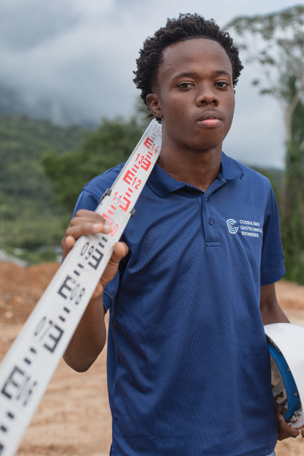 A young man in a blue shirt is holding a measuring tape.
