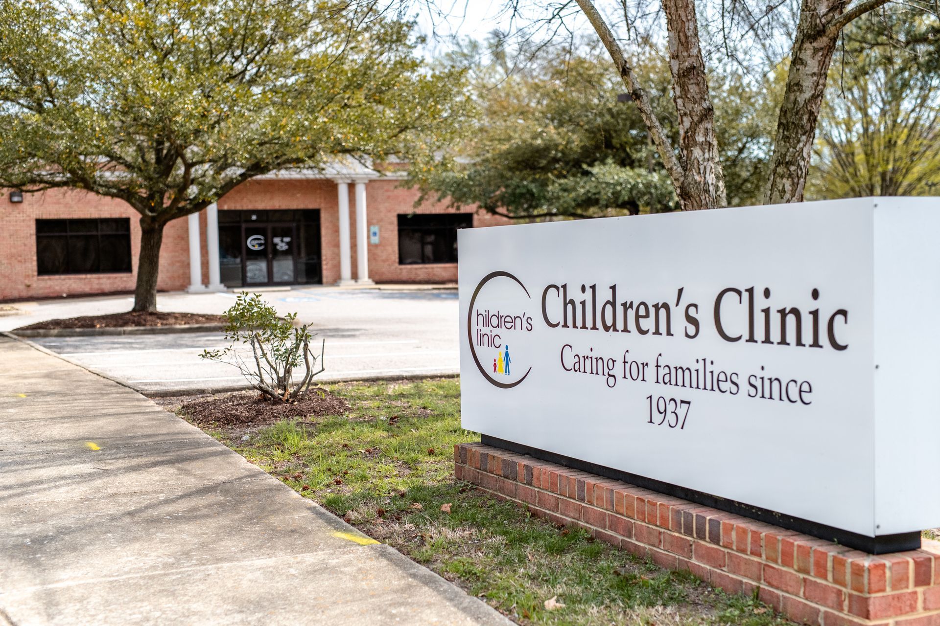 A Children's Clinic sign is in front of a brick building.