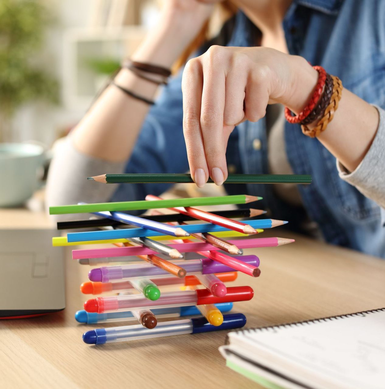 A person is stacking colored pencils on top of each other