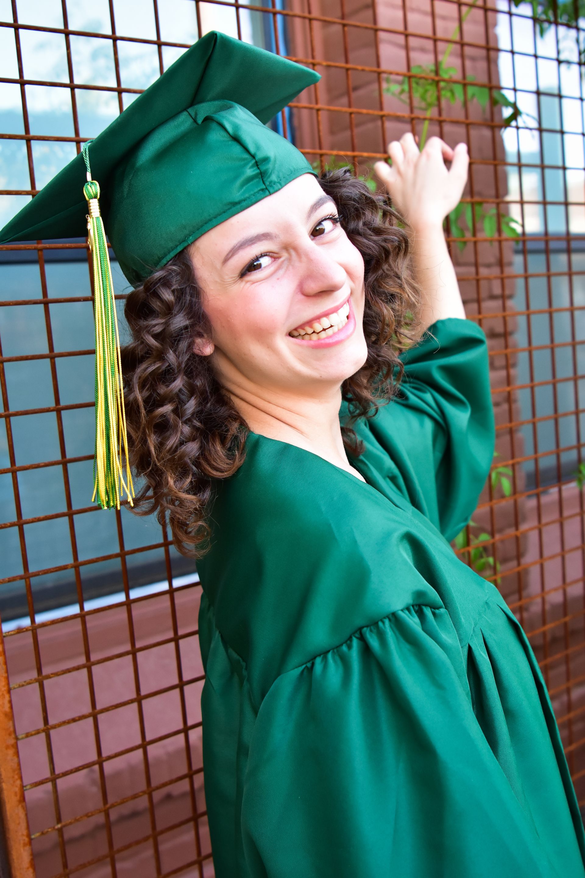 A woman is wearing a green graduation cap and gown.