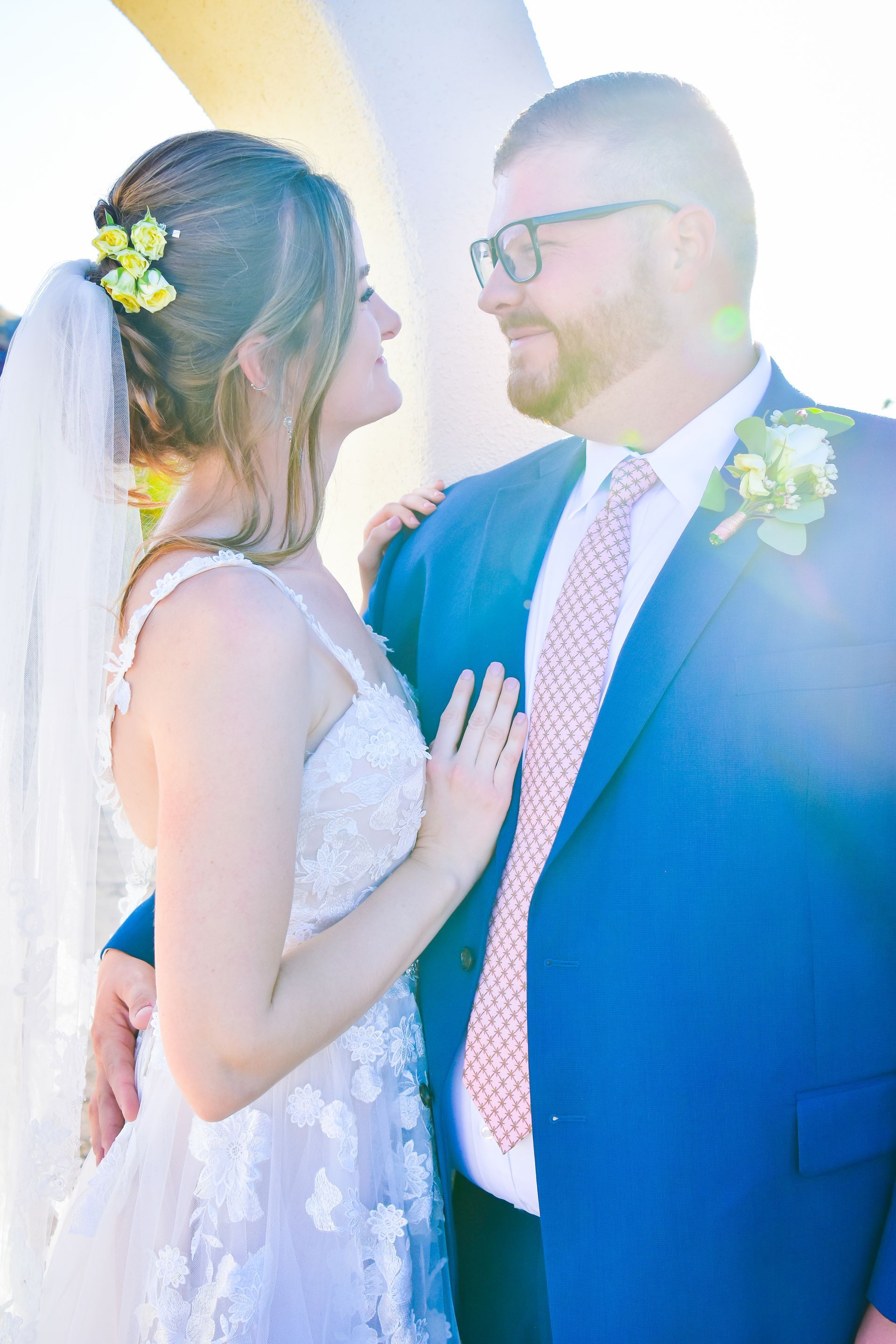 A bride and groom are standing next to each other and looking at each other.