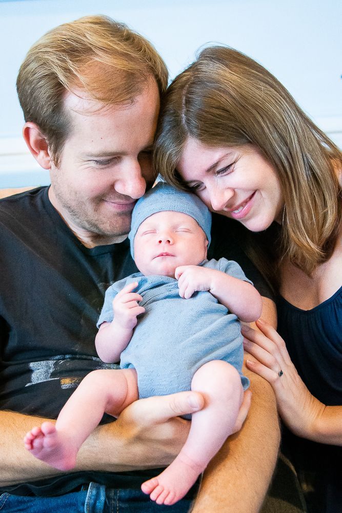 A man and woman are holding a newborn baby in their arms.