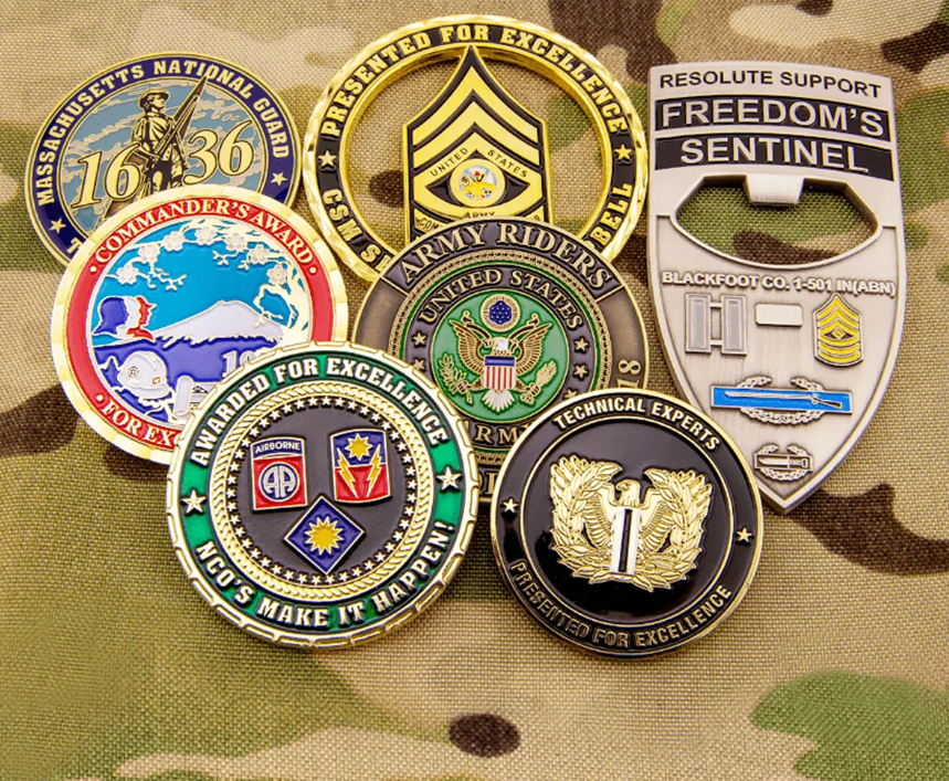 Collection of military challenge coins with various emblems and text against a camouflage background.