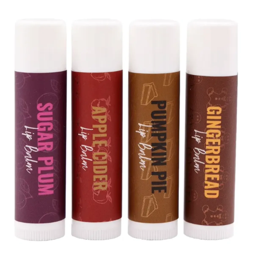 Four lip balm tubes: sugar plum (purple), apple cider (red), pumpkin pie (brown), and gingerbread (brown).