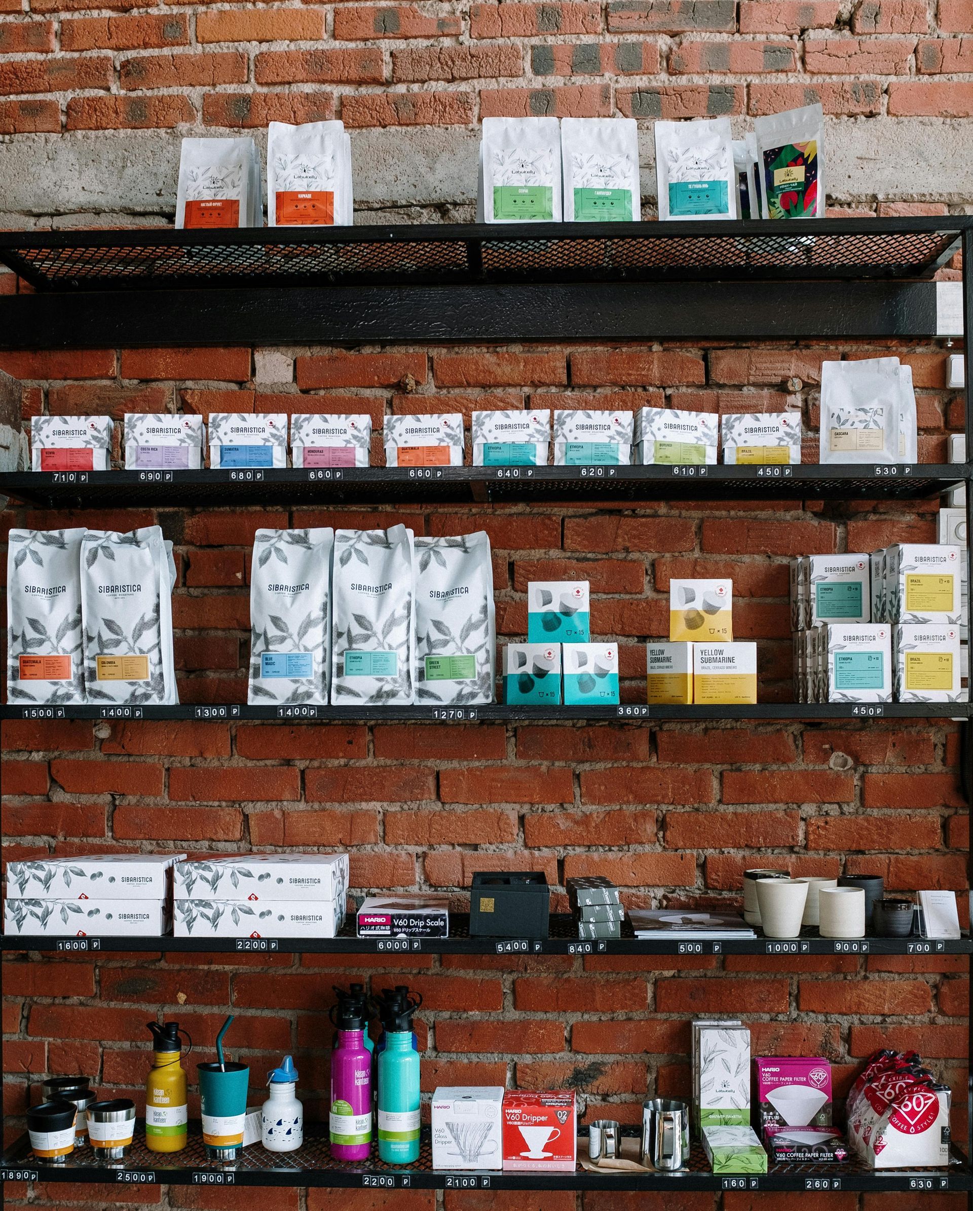 Shelves of colorful packaged coffee and tea products against a brick wall.
