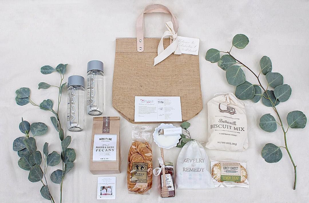 A gift bag with water bottles, snacks, and eucalyptus. Light colors, natural theme.