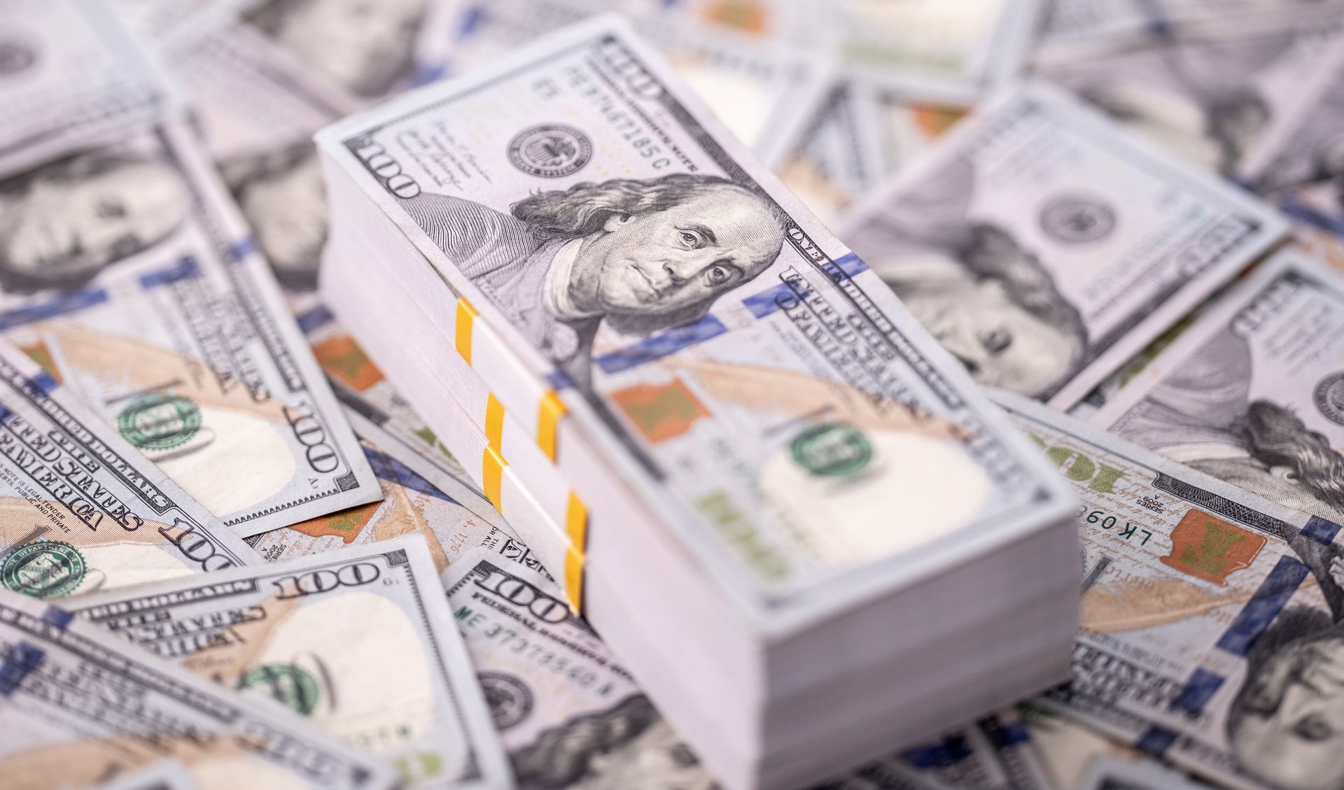 Stack of $100 bills on top of scattered bills.