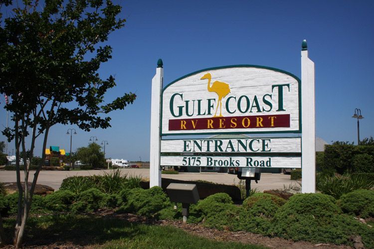 Sign for Gulf Coast RV Resort, white with green trim, tan pelican logo. Entrance, 5175 Brooks Road.