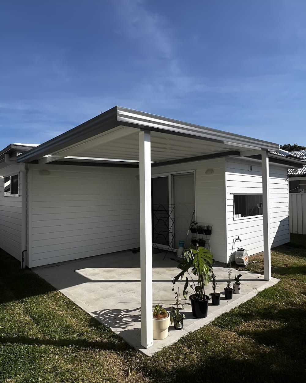 A White House With A Covered Porch And Potted Plants In Front Of It — Hunter Home Services in Thornton, NSW