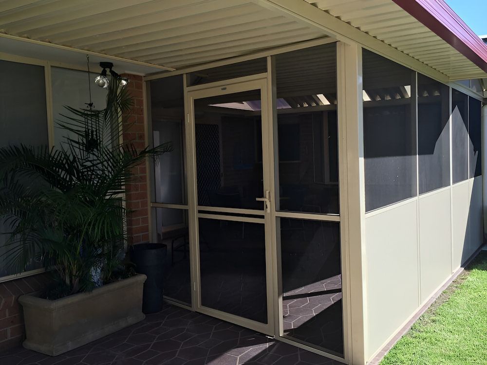 A Screened In Porch With A Door And A Potted Plant — Hunter Home Services in Cessnock, NSW