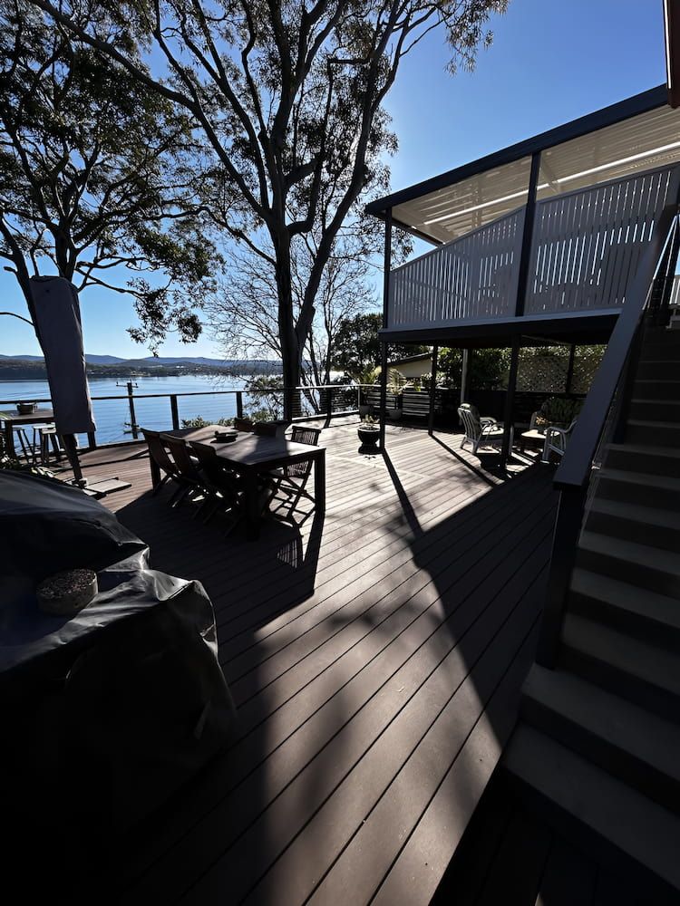 A Deck With Stairs Leading Up To A House Overlooking A Body Of Water — Hunter Home Services in Cessnock, NSW