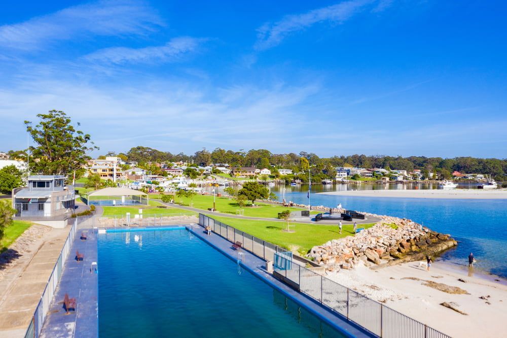 An Aerial View of A Large Swimming Pool Next to A Body of Water — Leisure Coast Powder Coaters in Huskisson, NSW