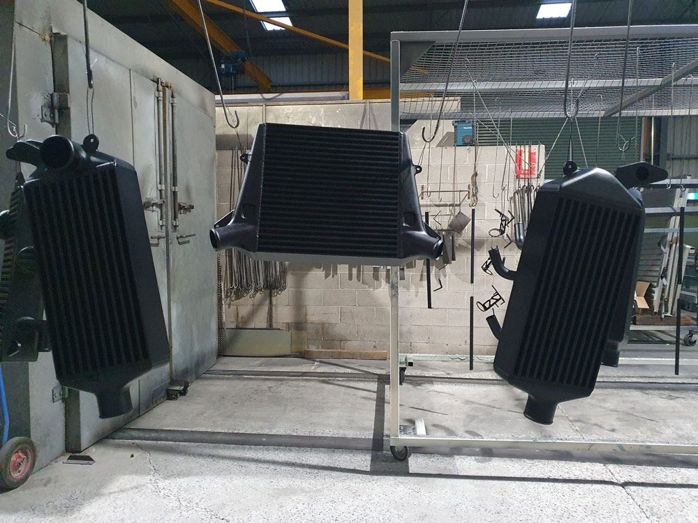 Two Black Radiators Are Hanging from The Ceiling in A Factory — Leisure Coast Powder Coaters in Moss Vale, NSW