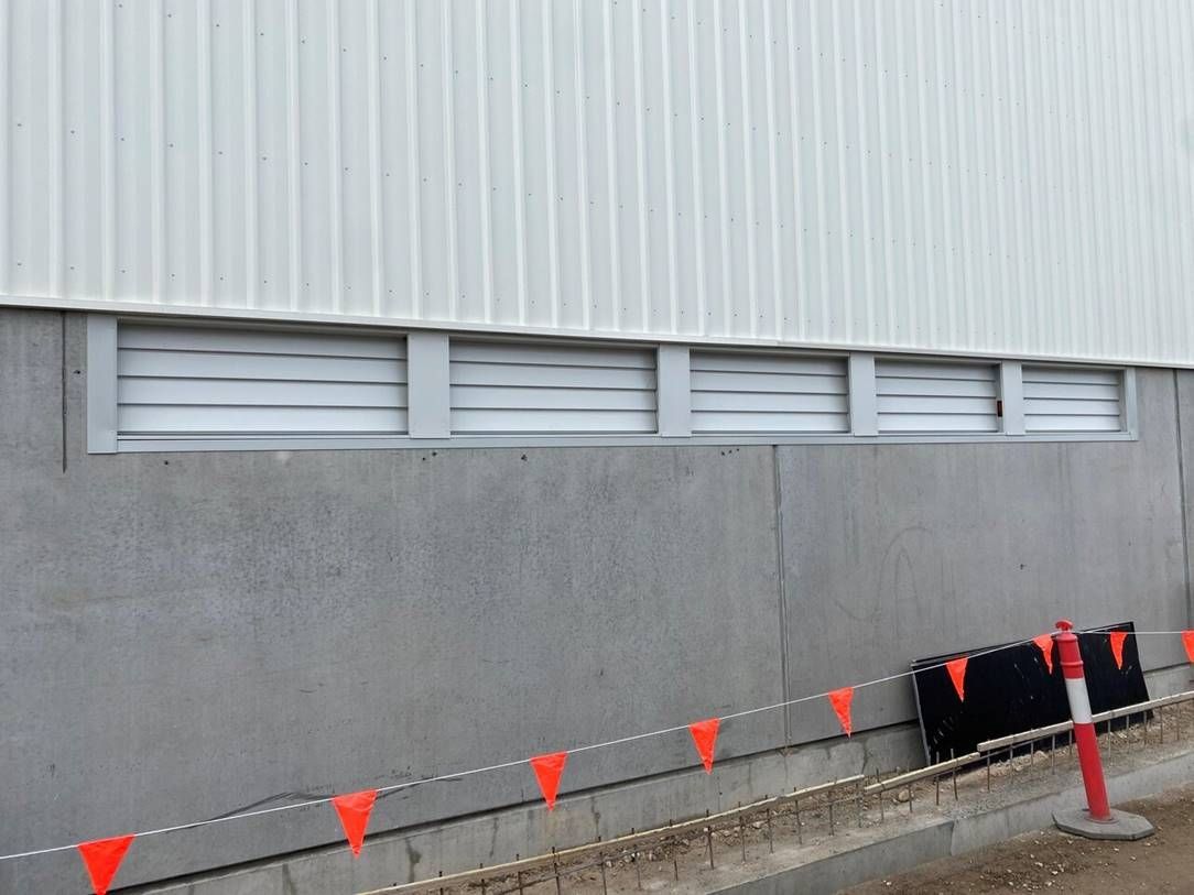 A White Building with A Window and Orange Flags on The Side of It — Leisure Coast Powder Coaters in Unanderra, NSW