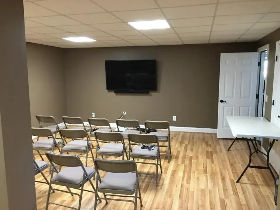 A small room set up for a presentation with chairs facing a large TV, with a folding table to the side.