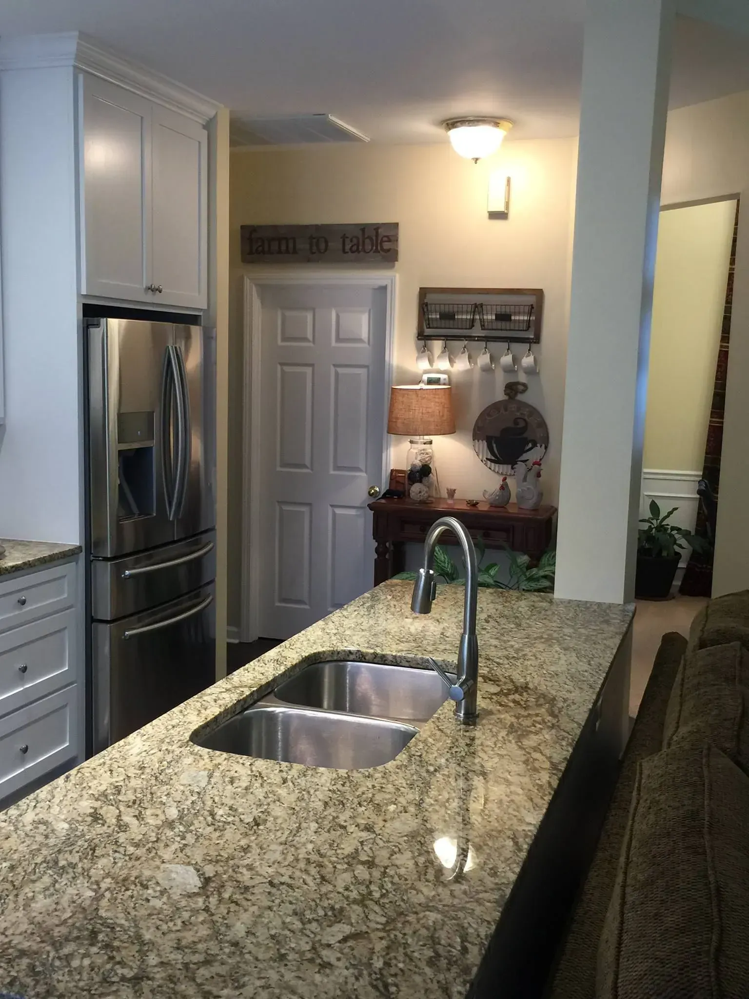 Kitchen with stainless steel refrigerator, granite countertops, and double sink.