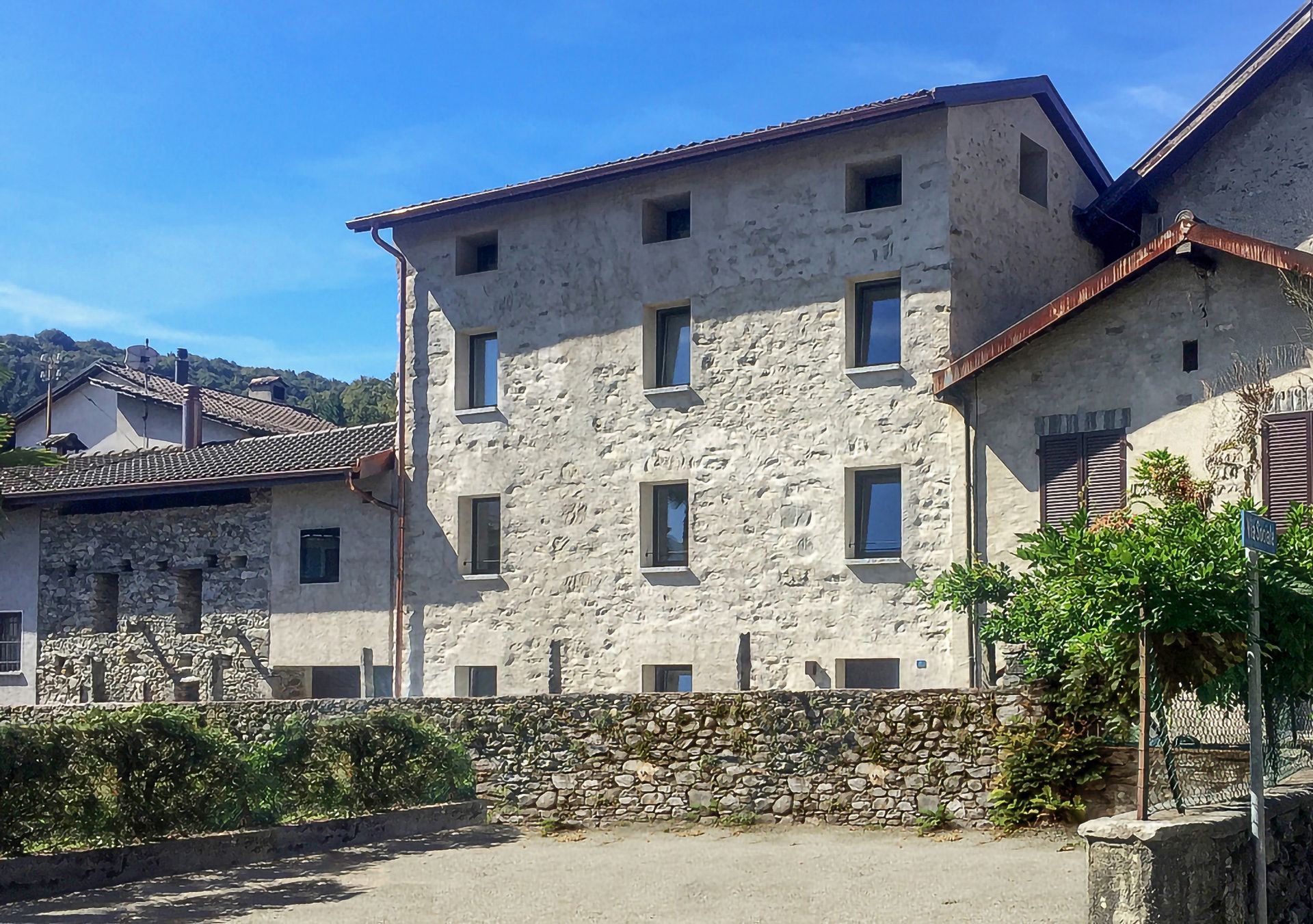 Edifici in pietra in un villaggio con cielo azzurro e un po' di verde.
