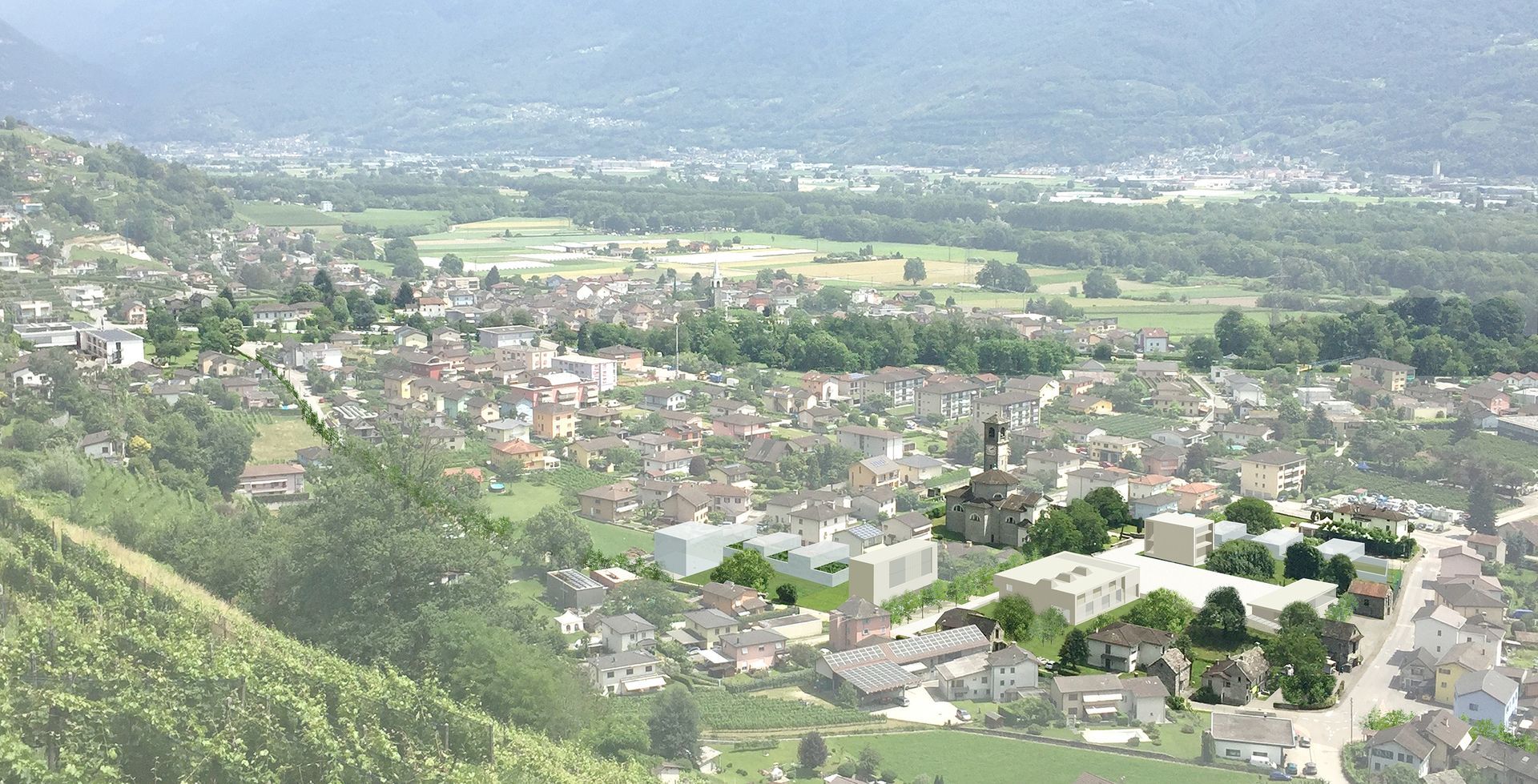 Vista aerea di una città in una valle con edifici, alberi e colline in lontananza.