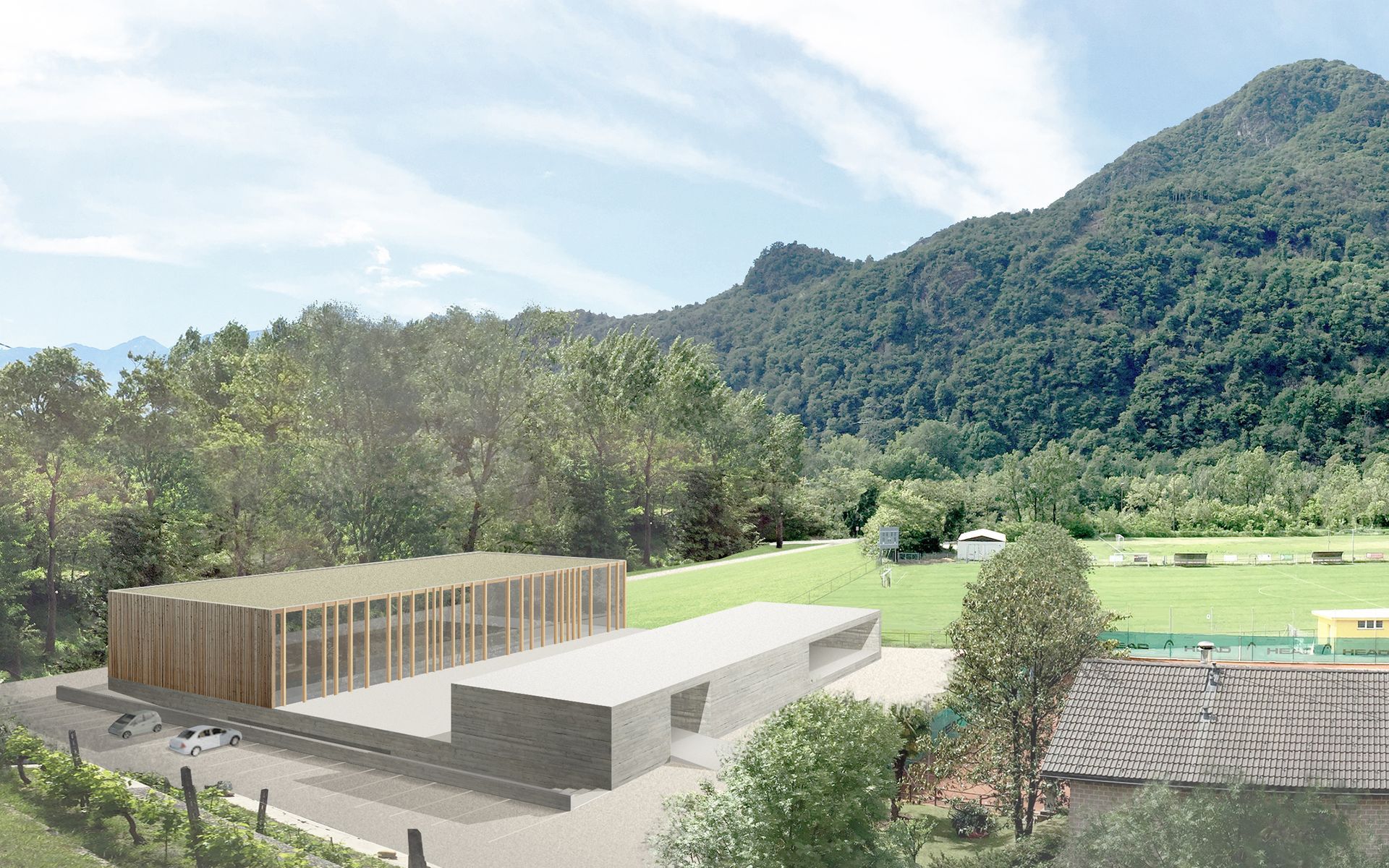 Due edifici moderni con esterni in legno e cemento immersi in un paesaggio verde con montagne sullo sfondo.