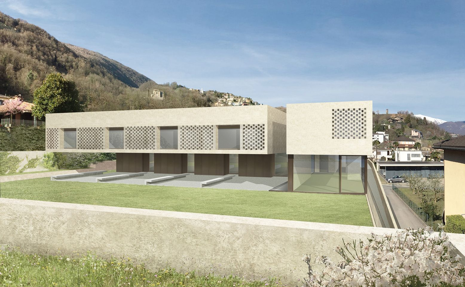 Moderno edificio beige con design geometrico; cortile erboso, montagne sullo sfondo, giornata di sole.