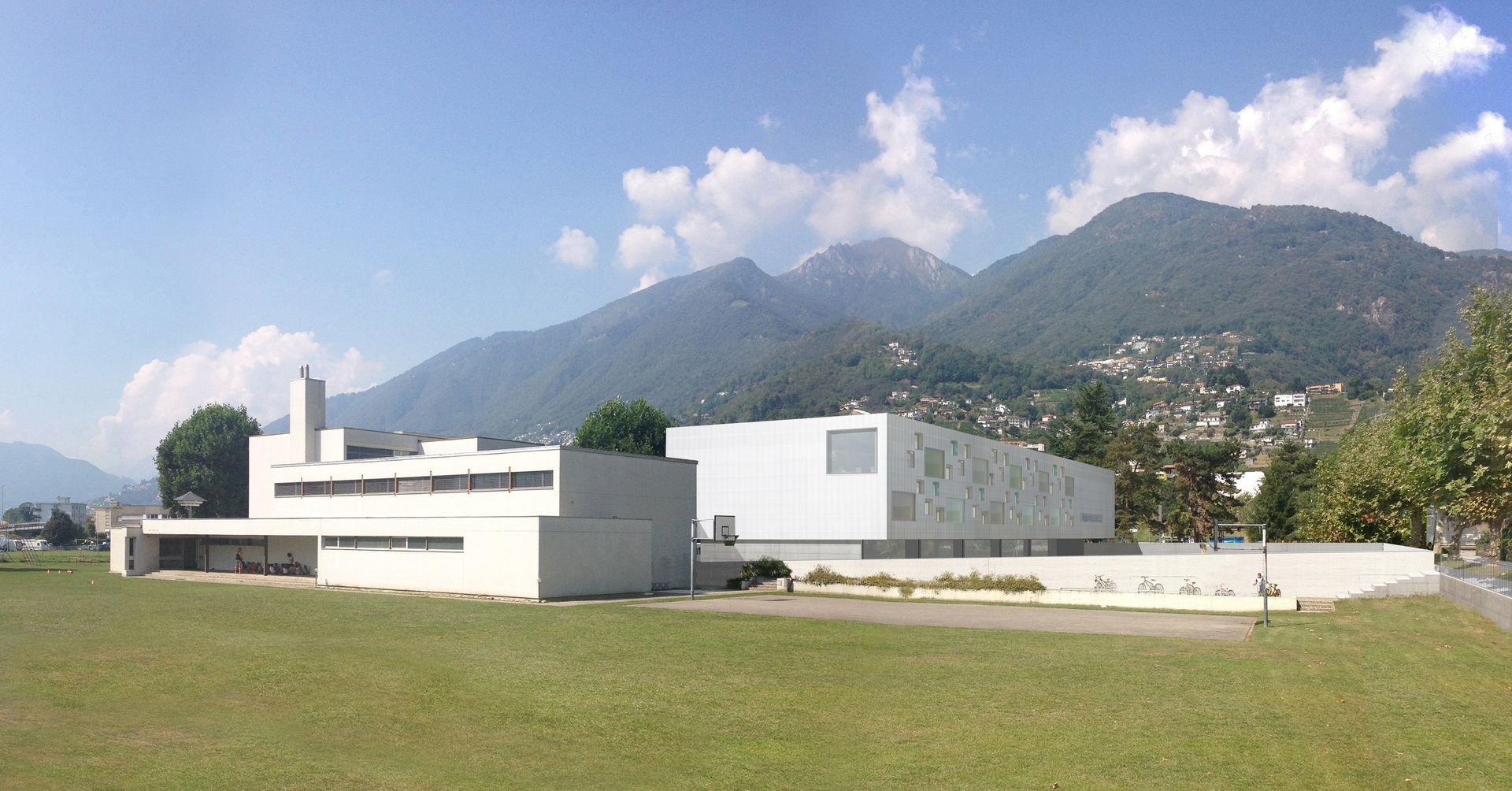 Moderno edificio bianco con montagne sullo sfondo e cielo azzurro.