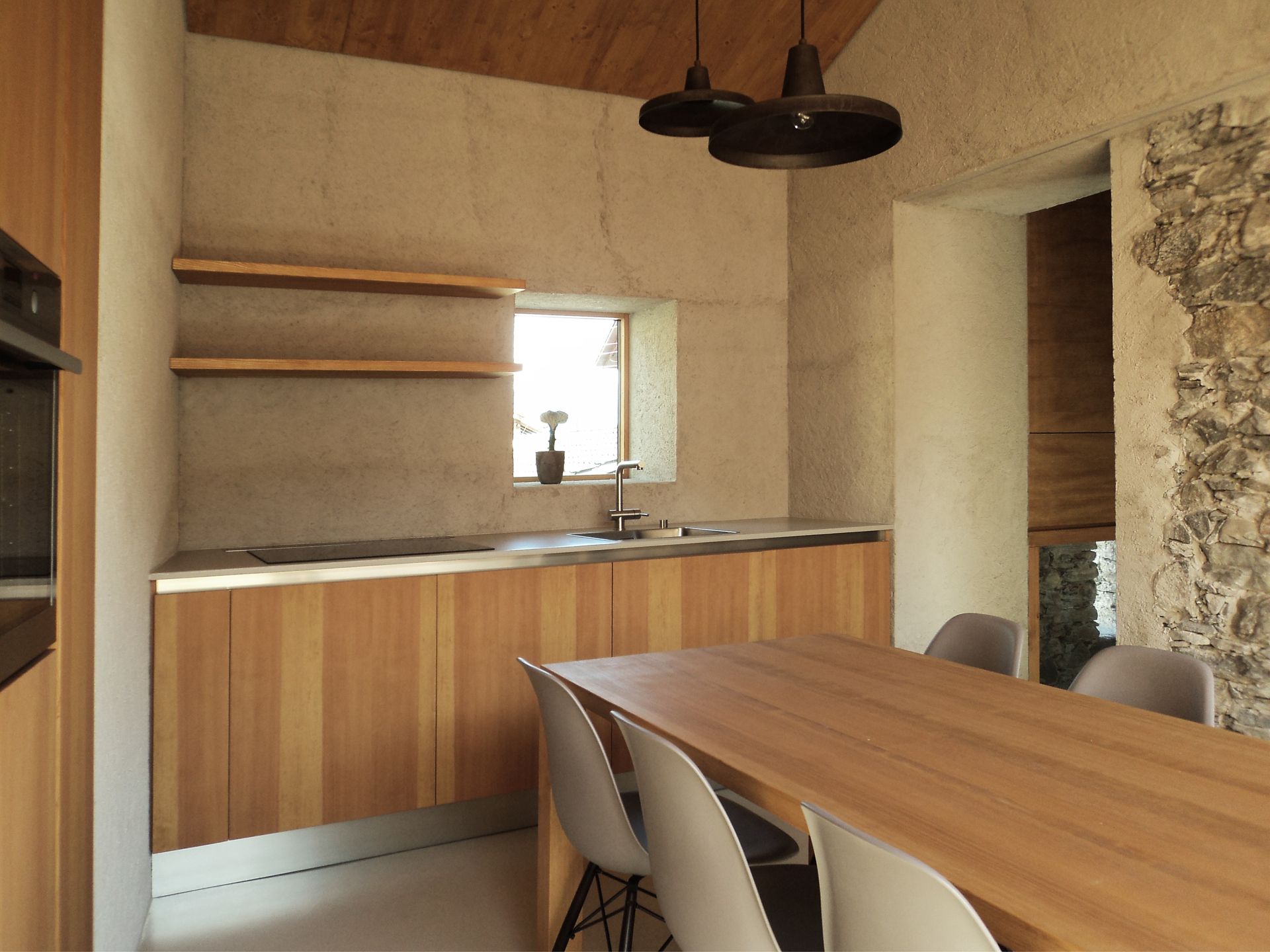 Cucina moderna con mobili in legno, parete in pietra e tavolo da pranzo con sedie.