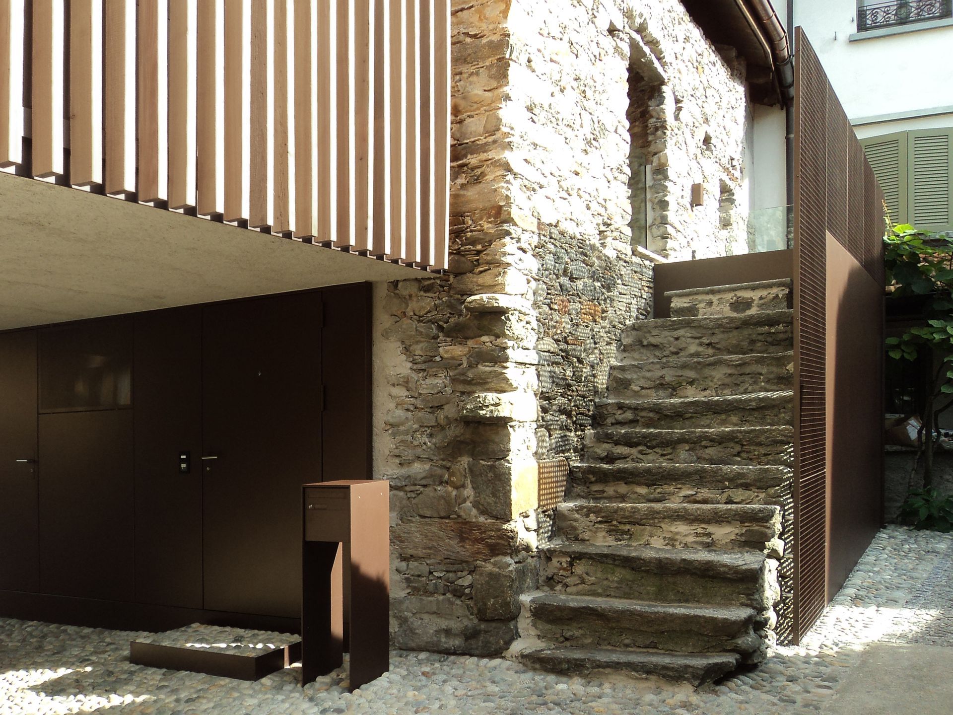 Edificio in pietra con scale esterne e dettagli in metallo marrone.