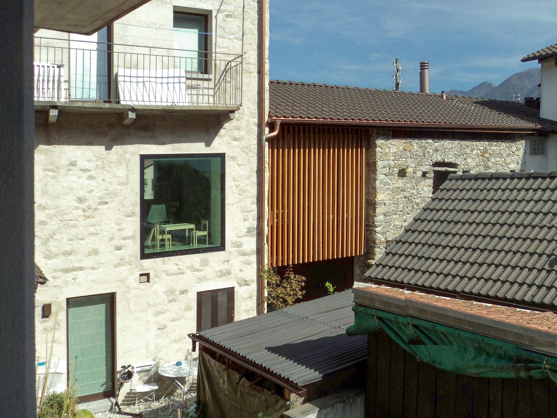 Edifici con rivestimenti in pietra e legno, tetti e uno scorcio di catena montuosa sullo sfondo.