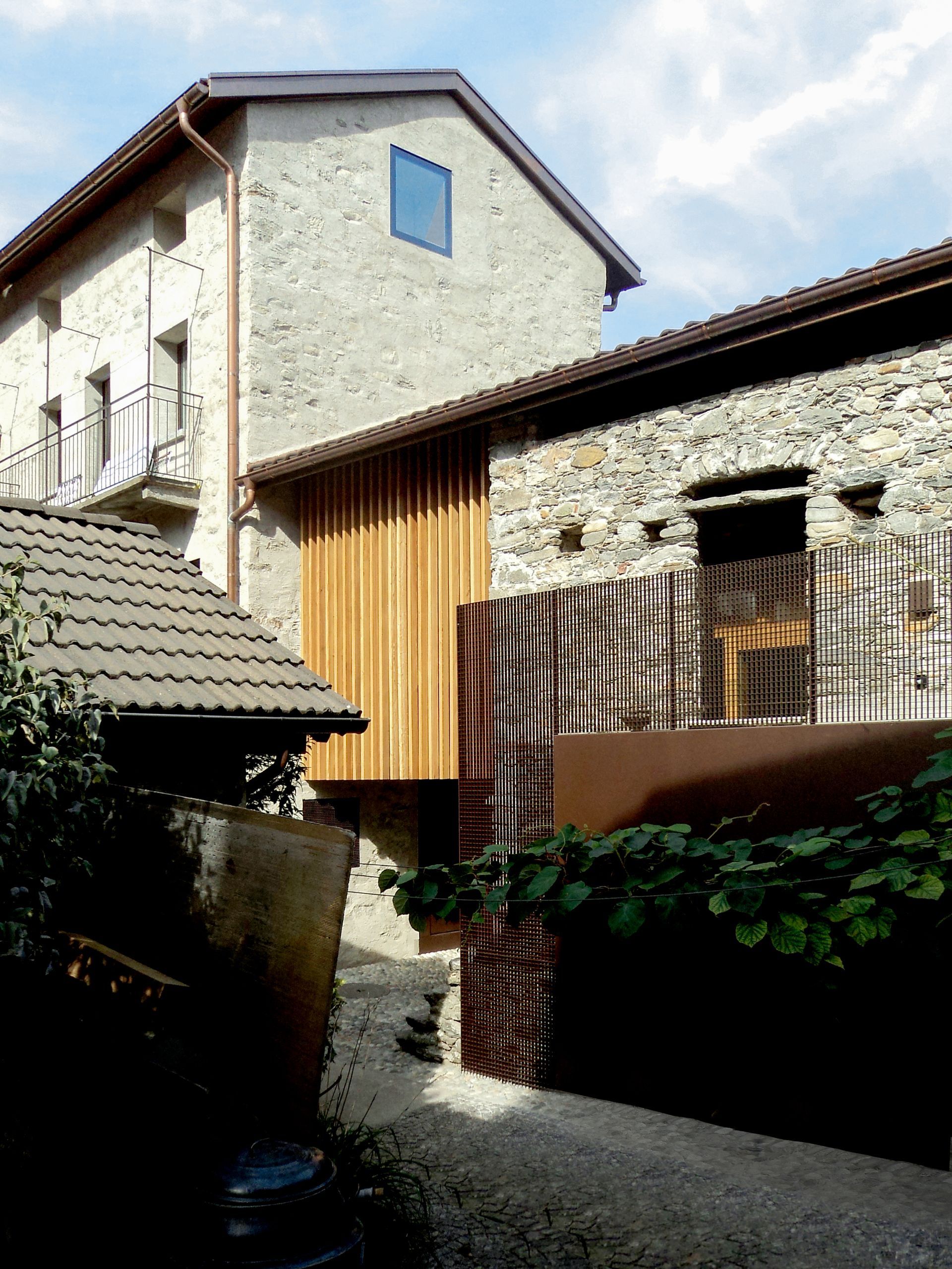 Edifici in pietra con dettagli in legno e un piccolo cortile.